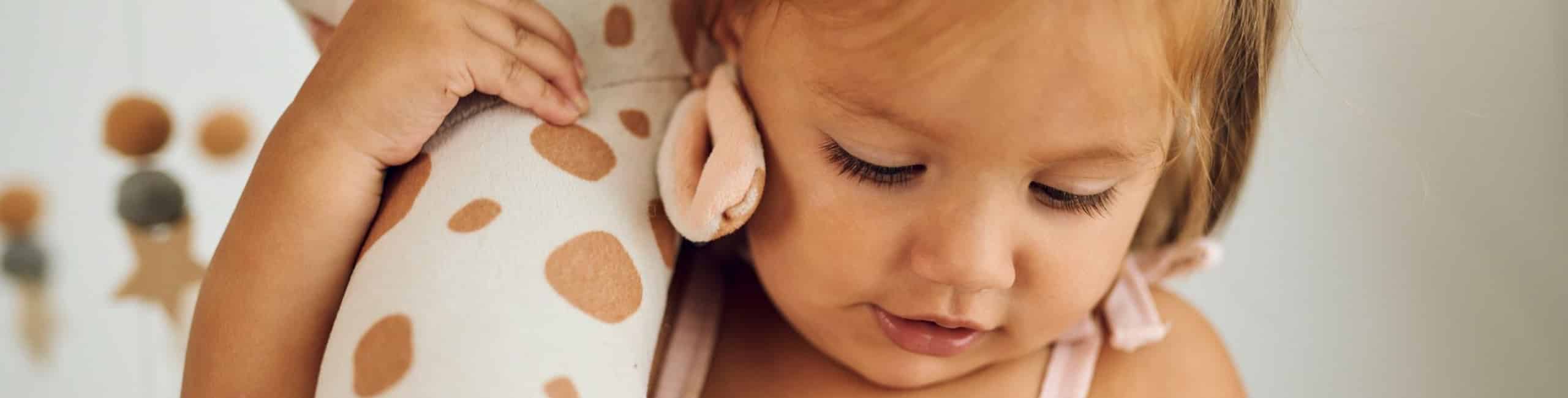 Djevojčica drži plišanu žirafu.