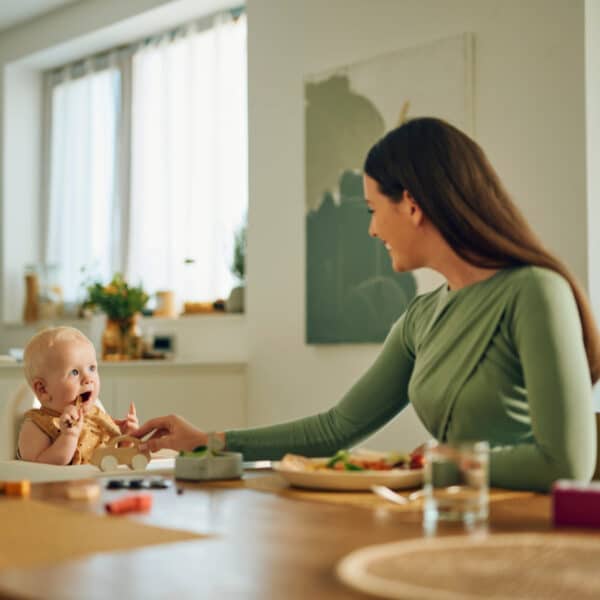 Beba i majka za stolom tijekom obroka.