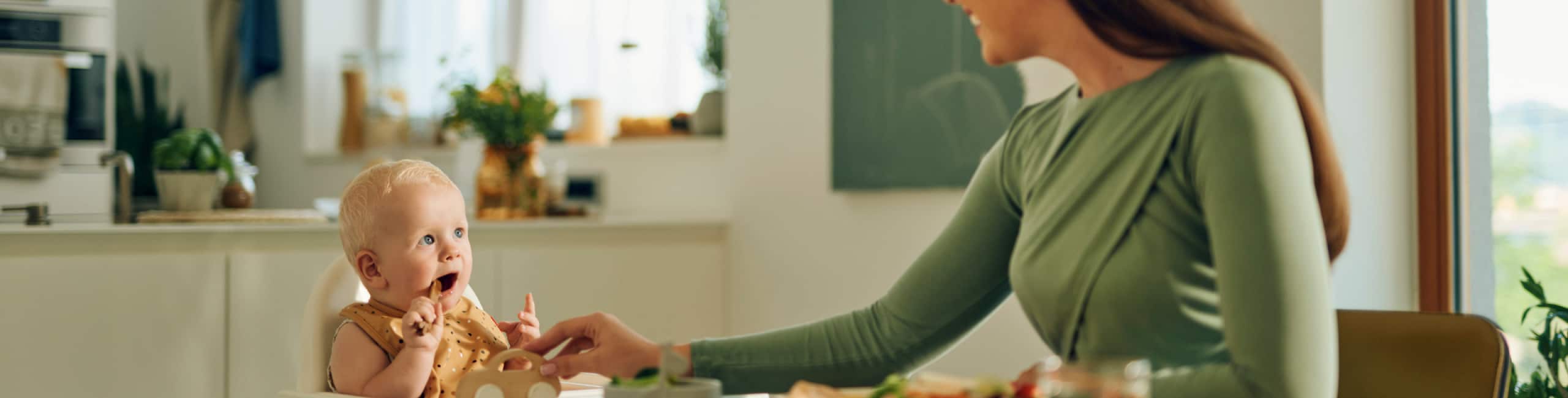 Beba i majka za stolom tijekom obroka.