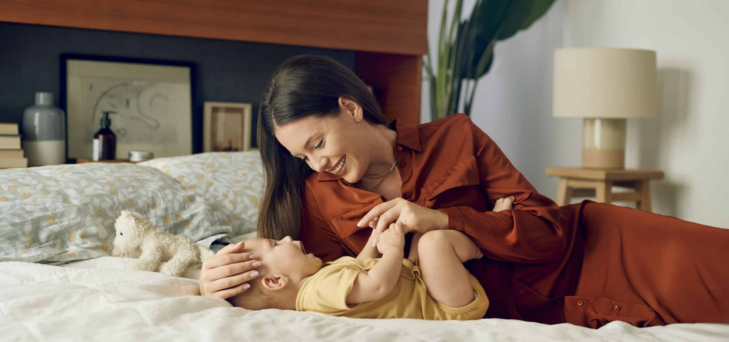 Majka se igra sa svojom bebom na krevetu.