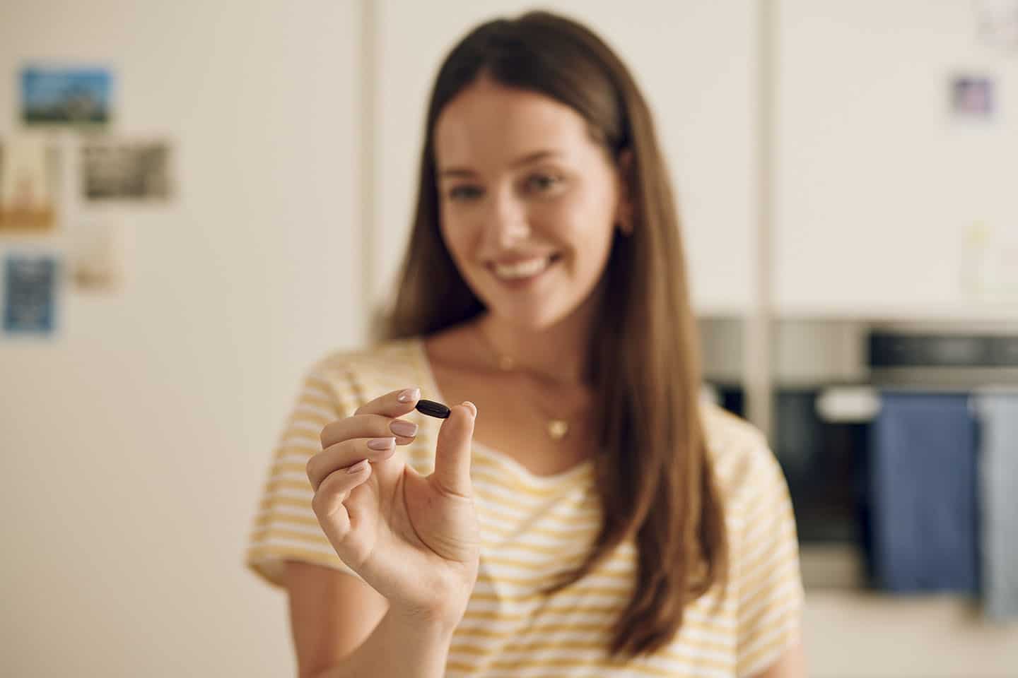 Žena drži prenatalnu kapsulu Novalac i priprema se za gutanje.