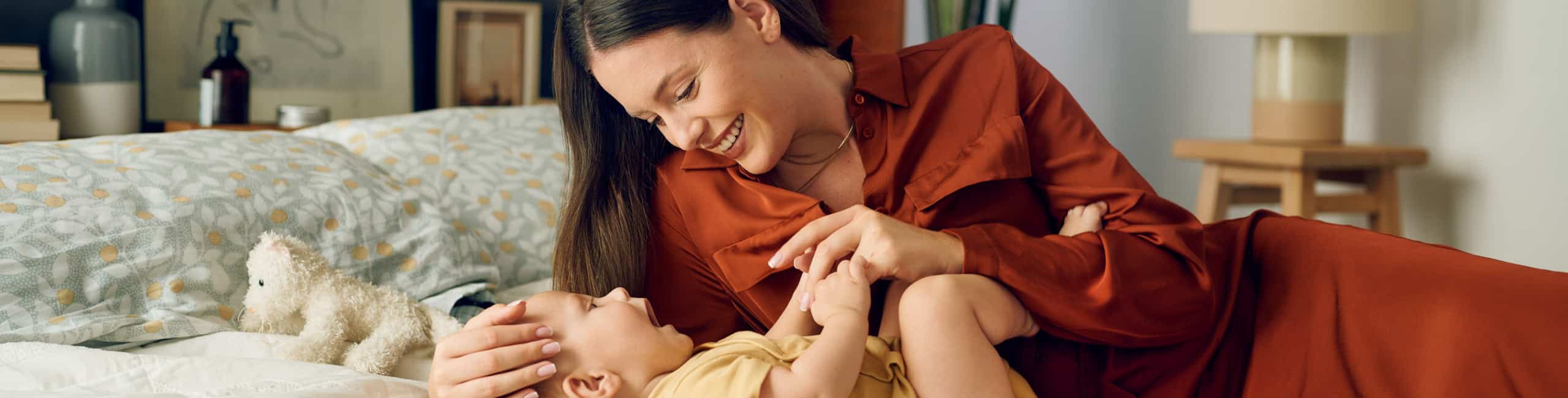 Majka se igra sa svojom bebom na krevetu.