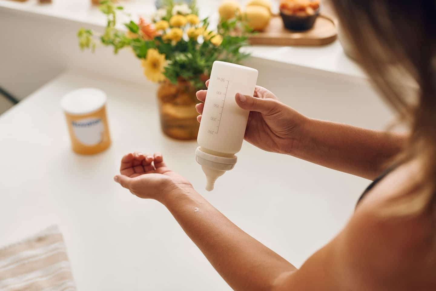 Mama priprema bočicu mlijeka u kuhinji - podrška za alergiju na proteine ​​kravljeg mlijeka.