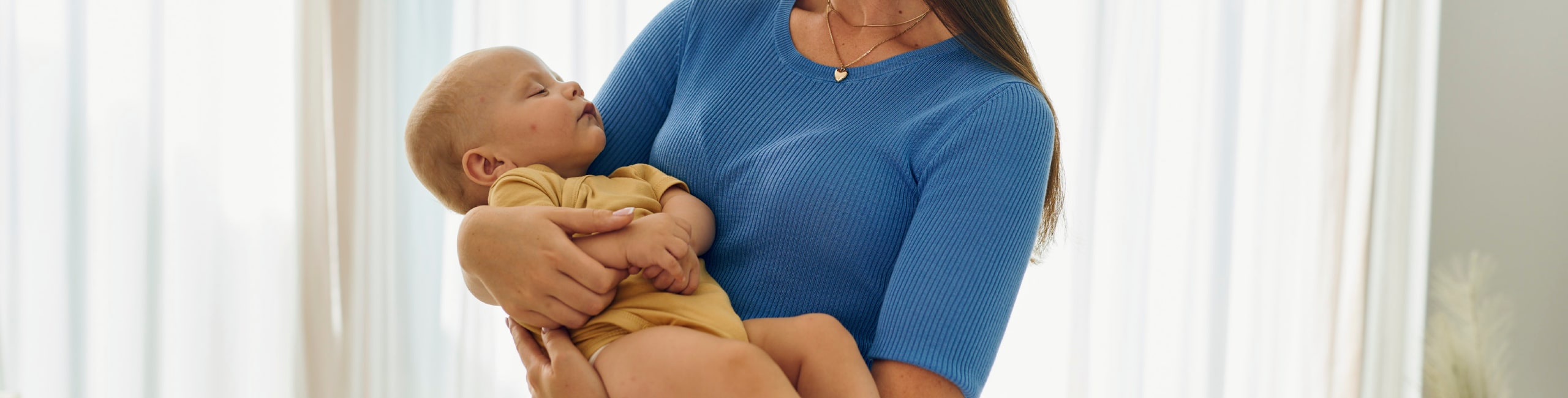 Majka drži novorođenče u svijetloj sobi