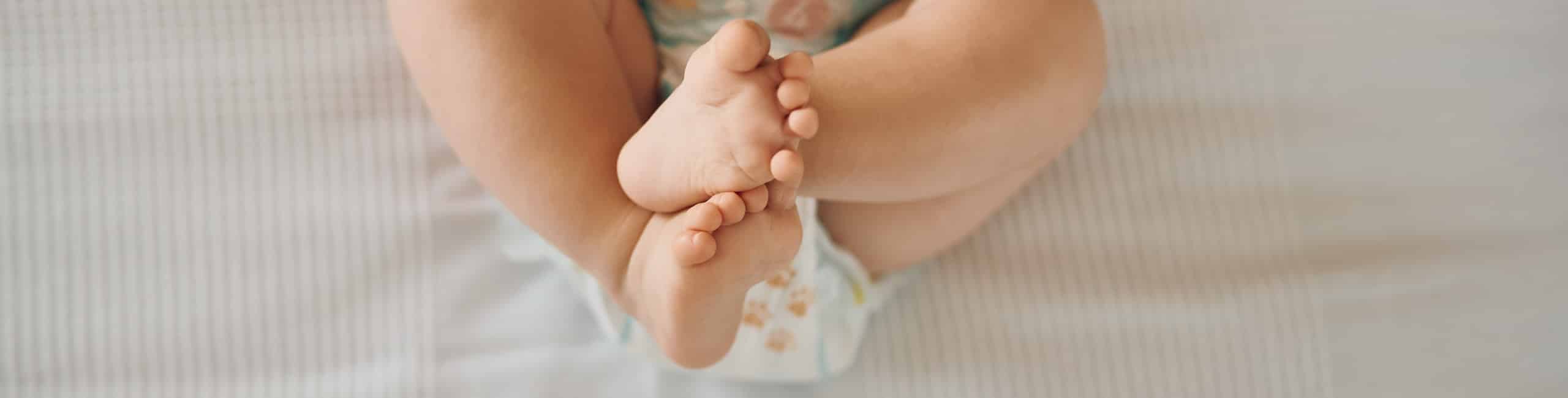 Beba leži s podignutim i prekriženim nogama, zatvor