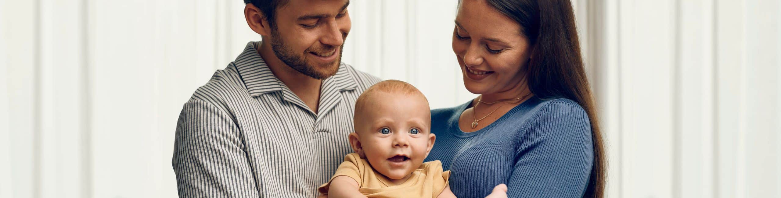 mama in oče držita v naročju dojenčka, srečna družina
